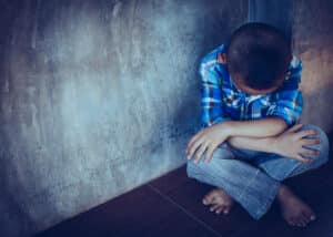 Small child withdraws while sitting on the floor due to trauma